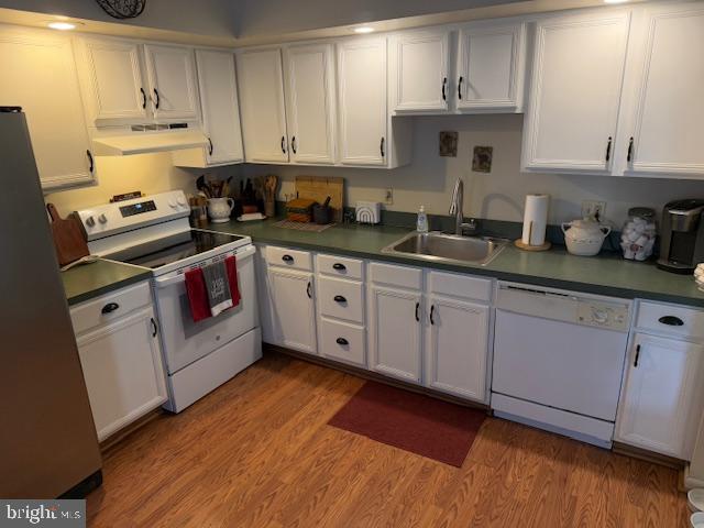 kitchen with white appliances, light hardwood / wood-style flooring, and white cabinets