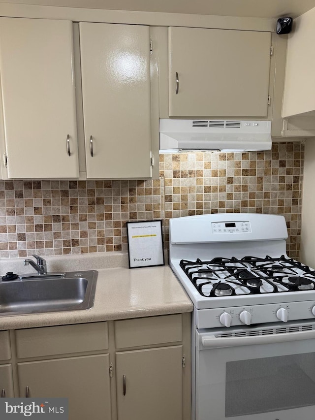 kitchen featuring white gas range, decorative backsplash, and sink