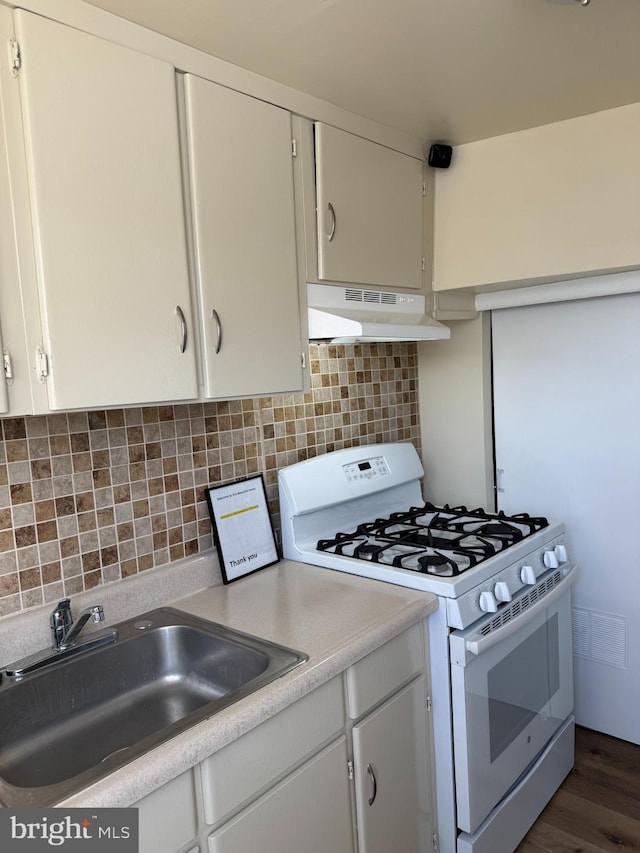 kitchen with decorative backsplash, sink, gas range gas stove, and white cabinets