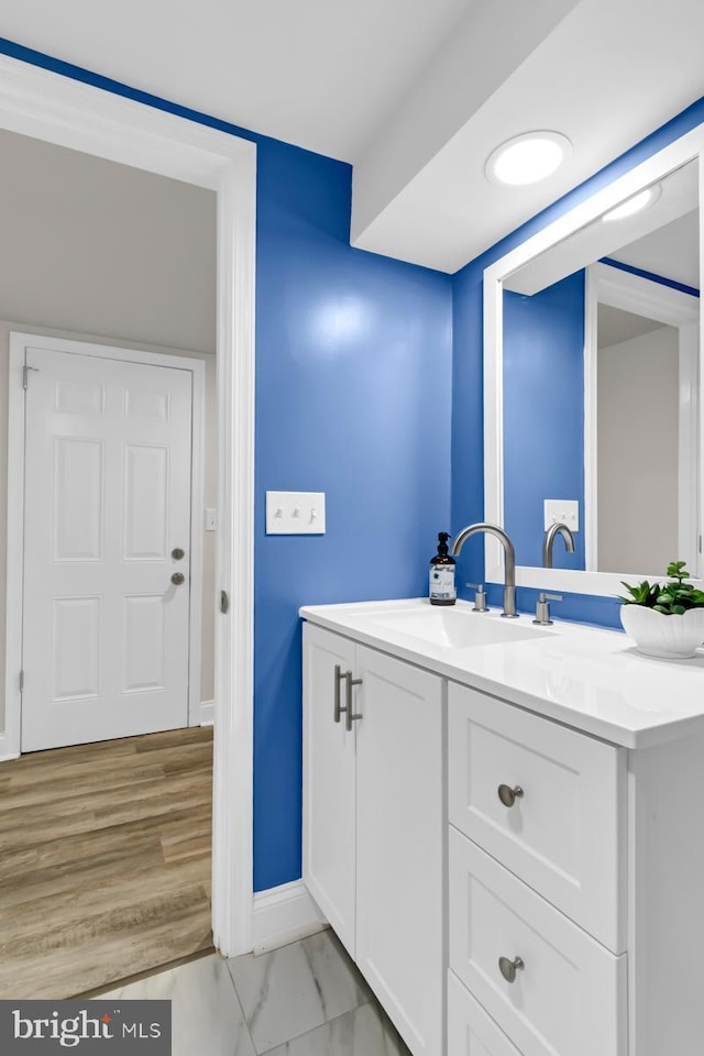 bathroom with marble finish floor, vanity, and baseboards