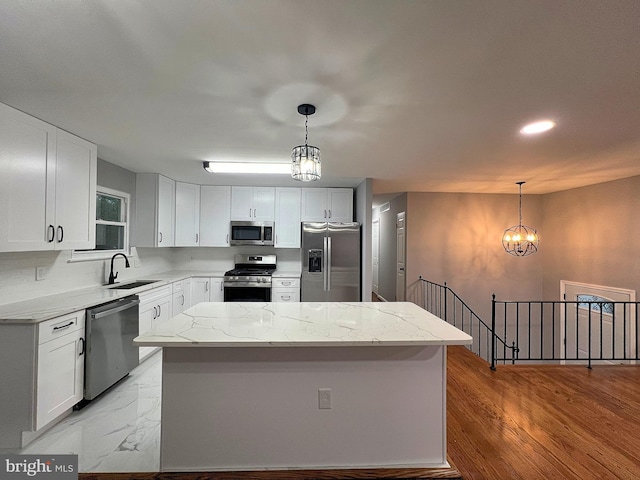 kitchen with decorative light fixtures, stainless steel appliances, and a center island