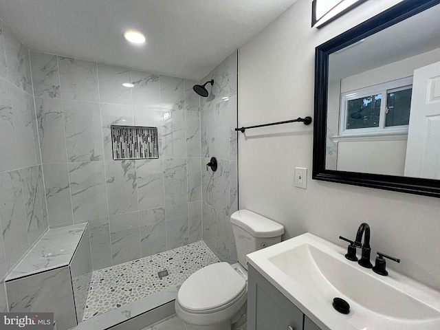 bathroom featuring vanity, toilet, and a tile shower