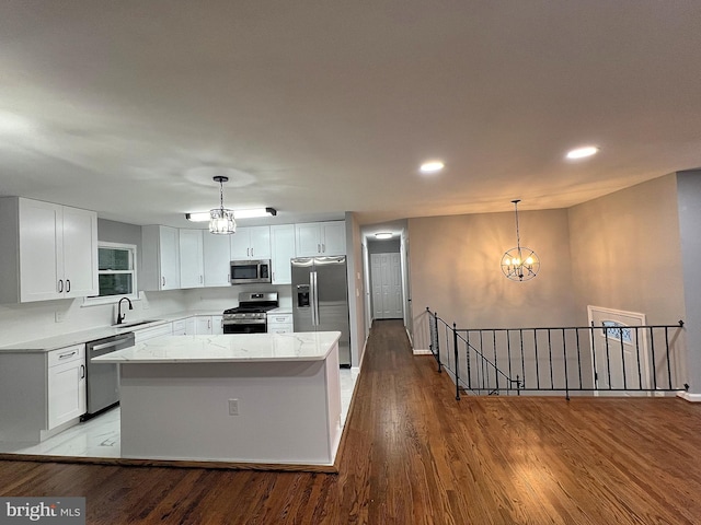 kitchen with sink, hanging light fixtures, stainless steel appliances, a center island, and white cabinets