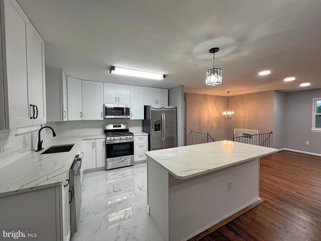 kitchen featuring white cabinetry, stainless steel appliances, hanging light fixtures, and a kitchen island