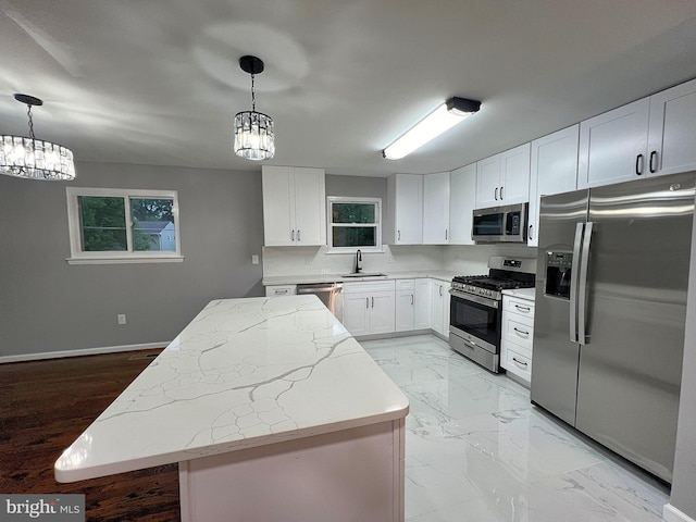 kitchen with a kitchen island, appliances with stainless steel finishes, pendant lighting, and white cabinets