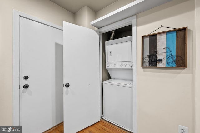 laundry room featuring hardwood / wood-style floors and stacked washing maching and dryer