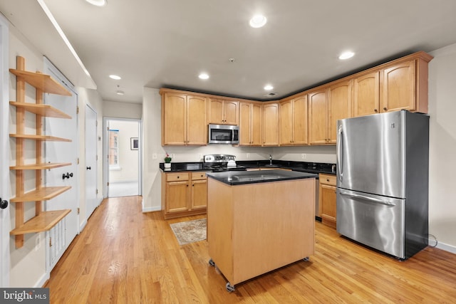 kitchen featuring light wood-type flooring, light brown cabinets, a center island, and appliances with stainless steel finishes