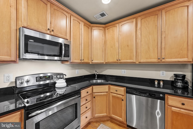 kitchen featuring stainless steel appliances, sink, and dark stone counters