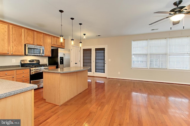 kitchen featuring stainless steel appliances, a kitchen island, pendant lighting, and light hardwood / wood-style flooring