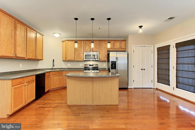 kitchen featuring sink, stainless steel appliances, a center island, light hardwood / wood-style floors, and decorative light fixtures