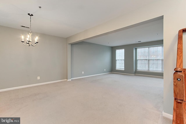 empty room with light carpet and a chandelier