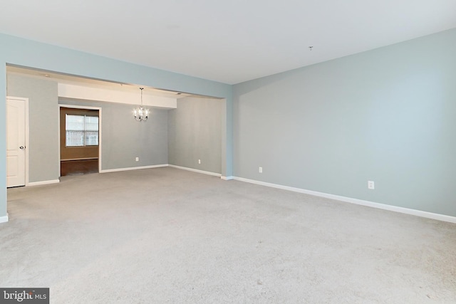 carpeted spare room with a chandelier