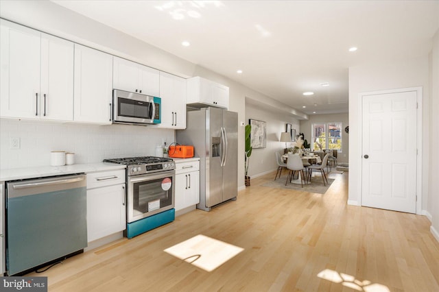 kitchen with backsplash, stainless steel appliances, light hardwood / wood-style floors, light stone countertops, and white cabinets