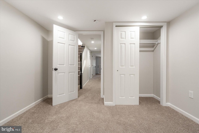 unfurnished bedroom featuring light colored carpet and a closet