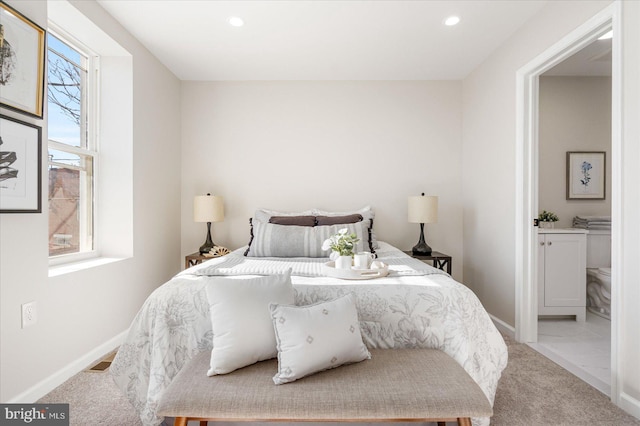 bedroom featuring connected bathroom and light carpet