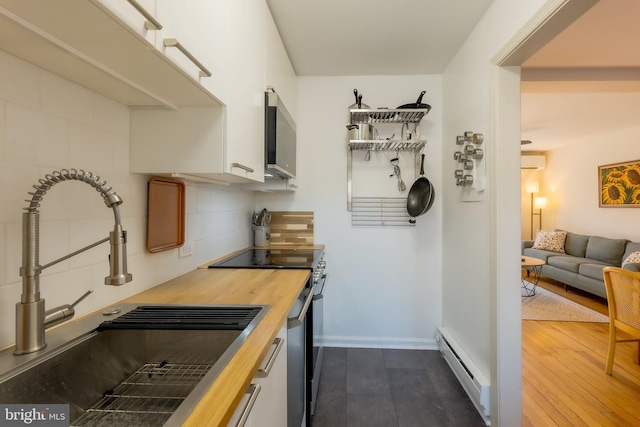 kitchen with wood counters, white cabinetry, sink, backsplash, and a baseboard heating unit