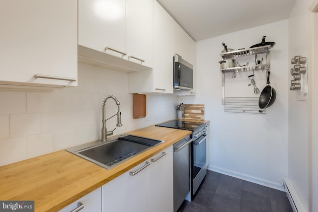 kitchen featuring sink, a baseboard radiator, stainless steel appliances, and white cabinets