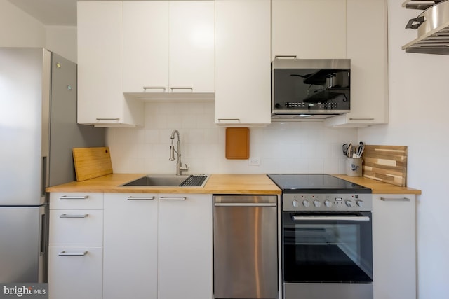 kitchen with stainless steel appliances, white cabinetry, sink, and decorative backsplash