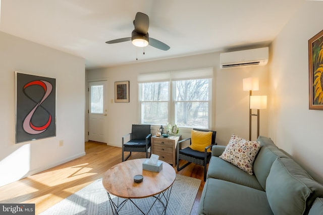 living room featuring ceiling fan, an AC wall unit, and light hardwood / wood-style floors