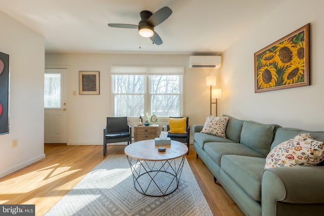 living room featuring ceiling fan, a wall unit AC, and light wood-type flooring