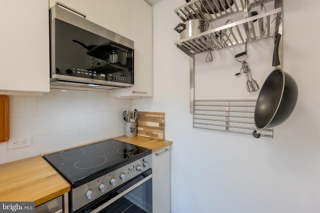 kitchen featuring tasteful backsplash, white cabinetry, appliances with stainless steel finishes, and butcher block counters