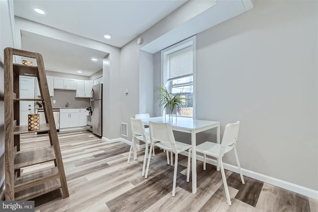 dining area with sink and light hardwood / wood-style floors