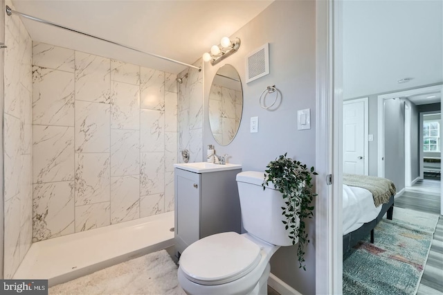 bathroom with vanity, tiled shower, and toilet