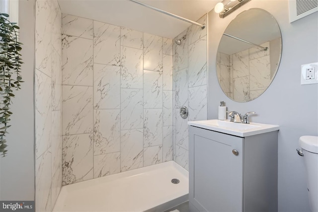 bathroom with vanity, a tile shower, and toilet