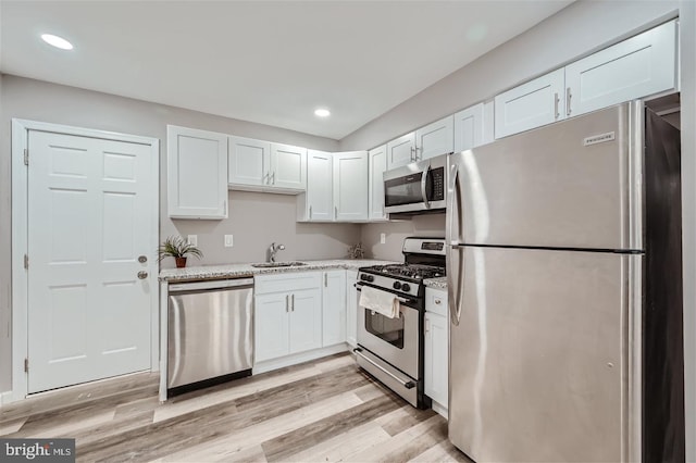 kitchen featuring appliances with stainless steel finishes, sink, white cabinets, and light wood-type flooring