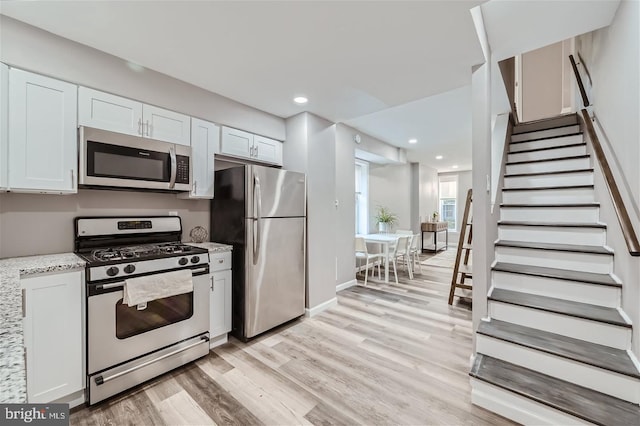 kitchen featuring light stone counters, light hardwood / wood-style flooring, stainless steel appliances, and white cabinets