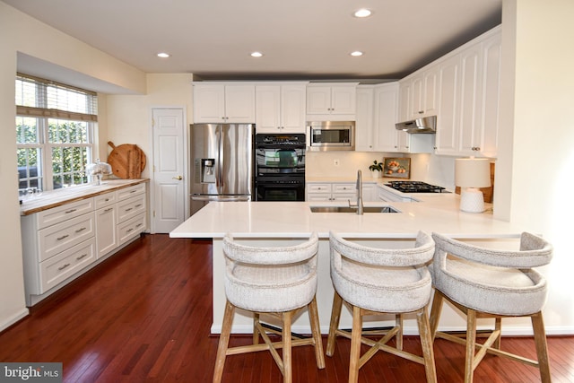 kitchen featuring sink, a breakfast bar area, appliances with stainless steel finishes, white cabinetry, and kitchen peninsula