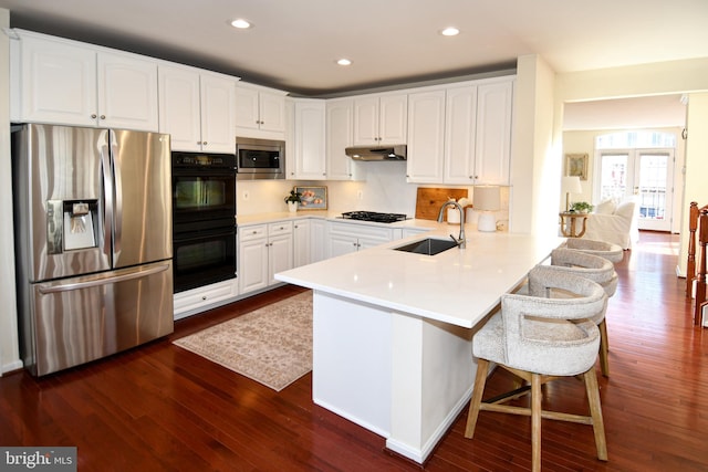 kitchen with sink, black appliances, kitchen peninsula, and white cabinets