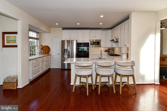 kitchen featuring white cabinetry, sink, stainless steel appliances, and a breakfast bar