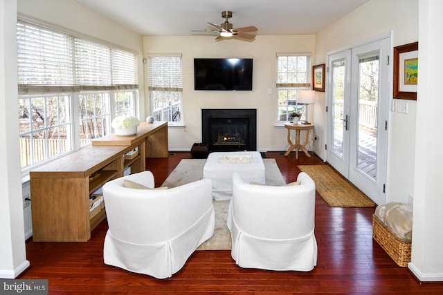 living room with a wealth of natural light, dark wood-type flooring, and ceiling fan