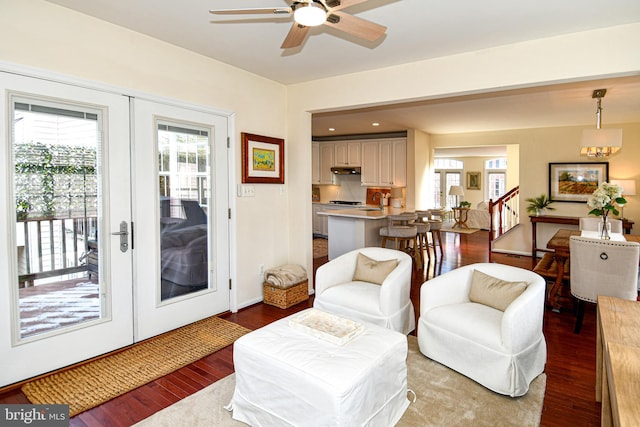 living room featuring hardwood / wood-style floors, ceiling fan with notable chandelier, and french doors