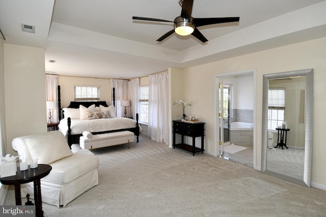 bedroom with light colored carpet, connected bathroom, and a raised ceiling