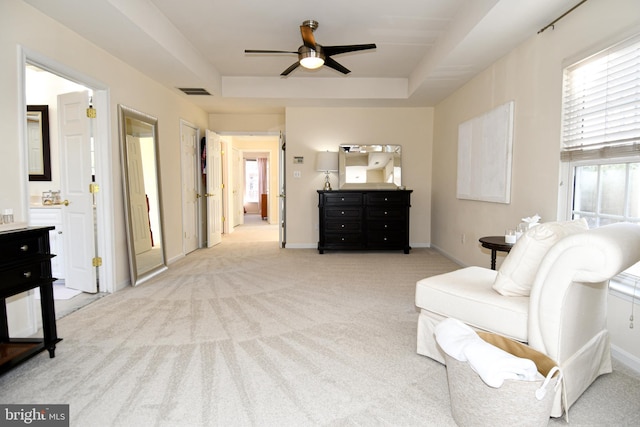 living area with light carpet, a tray ceiling, and ceiling fan