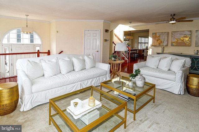 living room with ceiling fan with notable chandelier and ornamental molding