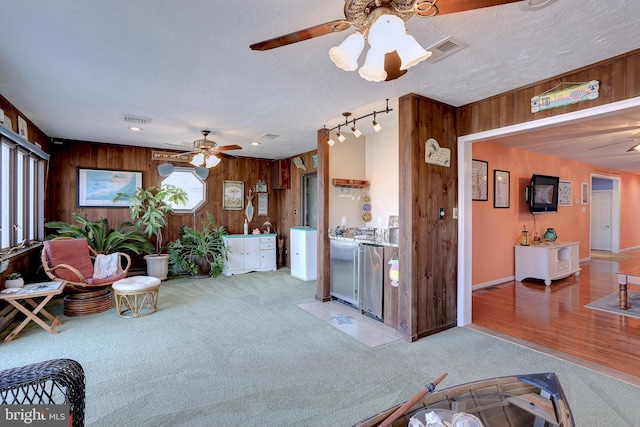 living room with light colored carpet, ceiling fan, and wood walls