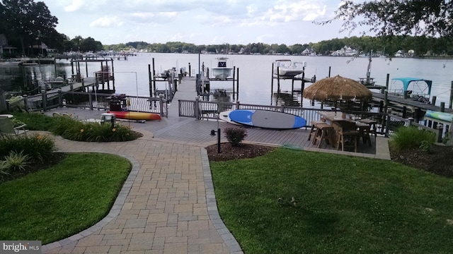 view of dock with a yard and a water view