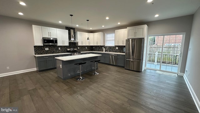 kitchen featuring a center island, a kitchen breakfast bar, gray cabinets, stainless steel appliances, and white cabinets