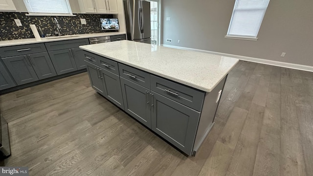 kitchen with sink, dark wood-type flooring, gray cabinets, appliances with stainless steel finishes, and tasteful backsplash