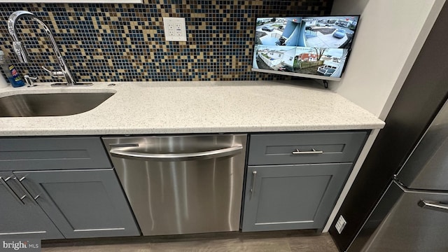 kitchen featuring gray cabinets, dishwasher, sink, and decorative backsplash