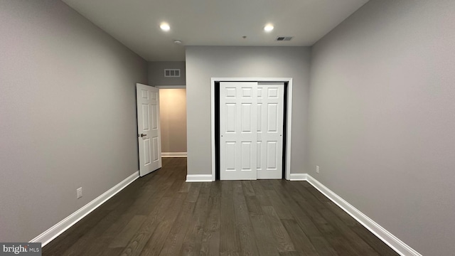 unfurnished bedroom featuring dark hardwood / wood-style floors and a closet