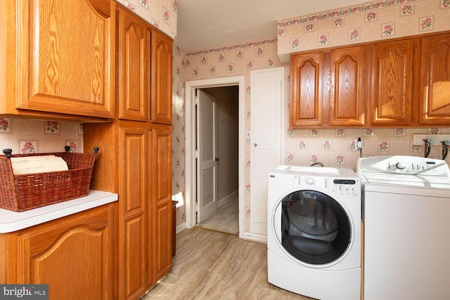 washroom with cabinets, washer and dryer, and light hardwood / wood-style flooring