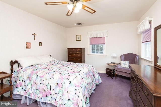 bedroom with multiple windows, dark carpet, and ceiling fan