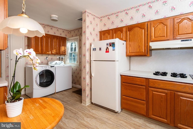 kitchen featuring pendant lighting, white appliances, and washer and dryer