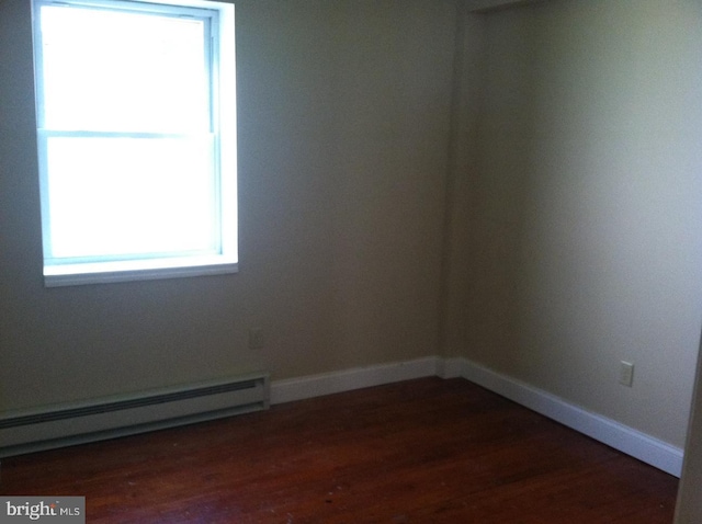 empty room with a baseboard heating unit and dark wood-type flooring