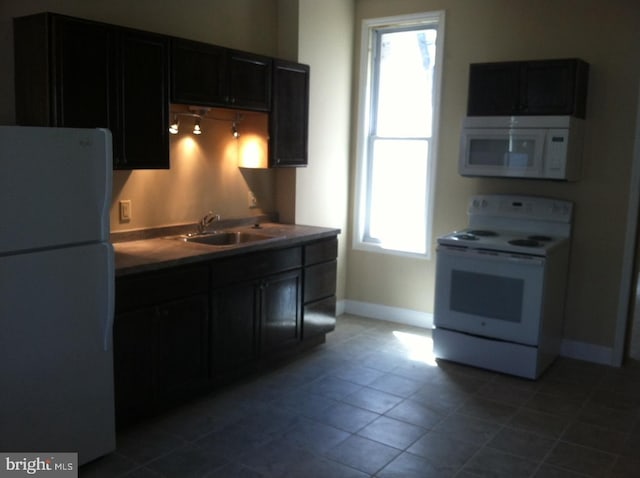 kitchen with sink, a wealth of natural light, tile patterned floors, and white appliances