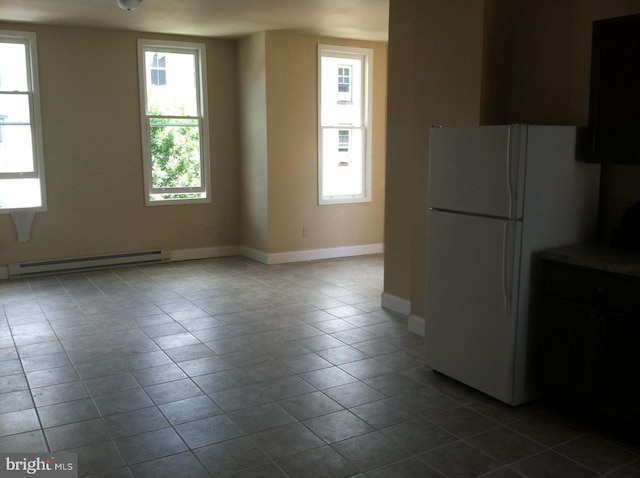 kitchen featuring a baseboard heating unit, light tile patterned floors, and white fridge